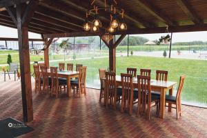 a dining area with wooden tables and chairs and a field at Pensiunea Willy Silvas in Tăşnad