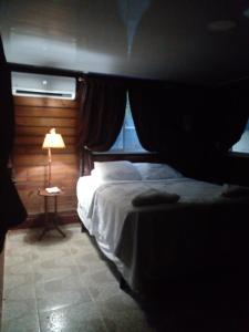 a bedroom with a bed and a lamp and a window at AO EO little wooden house honeymoon suite in Santiago de los Caballeros