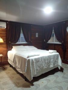 una camera da letto con un grande letto bianco con tende di AO EO little wooden house honeymoon suite a Santiago de los Caballeros