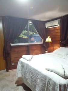 een slaapkamer met een groot bed en een raam bij AO EO little wooden house honeymoon suite in Santiago de los Caballeros