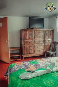 a bedroom with a dresser with a television and a bed at Casa Campesina La Fagua in La Calera