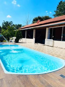 a swimming pool with a water fountain in front of a house at Chácara Sonho Realizado in São Pedro