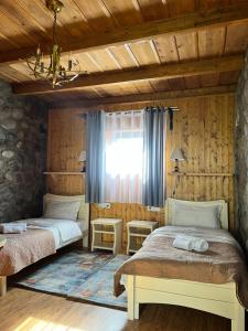two beds in a room with wooden walls and a window at Inn Harmony in Stepantsminda
