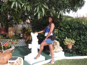 BUCKINGHAM VILLA -SUITES FULL KITCHEN-Rooms Variety في Buff Bay: امرأة تجلس على تمثال في حديقة