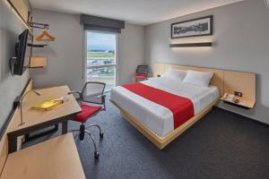 a hotel room with a bed and a desk and a window at City Express by Marriott Monterrey Norte in Monterrey
