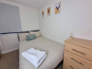 a small bedroom with a white bed and a dresser at Cozy 2 bed Flat in Southwark, Near Canary Wharf in London