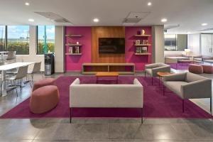 a lobby with chairs and tables and a purple wall at City Express by Marriott San Luis Potosi Zona Industrial in San Luis Potosí