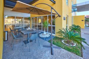 un restaurant avec des tables, des chaises et un parasol dans l'établissement City Express by Marriott Matamoros, à Matamoros