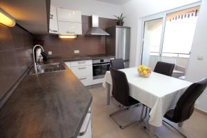cocina con mesa blanca con sillas y fregadero en Cvita apartments, en Trogir