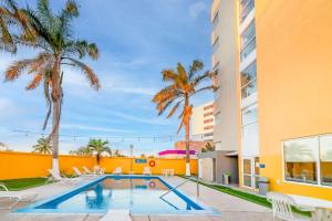 una piscina con palmeras y un edificio en City Express by Marriott Ciudad del Carmen en Ciudad del Carmen