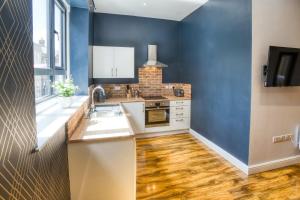 a kitchen with blue walls and wooden floors at Suite 1 - Class Apartment With King Sized Bed in Lincoln