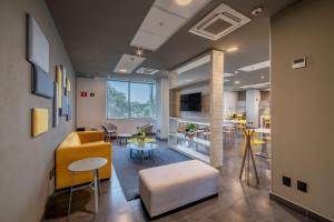 - un salon avec un canapé jaune et une table dans l'établissement City Express Plus by Marriott Guadalajara Palomar, à Guadalajara