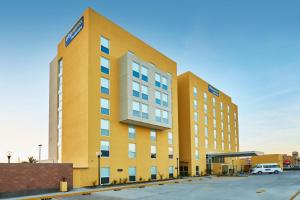 a large yellow building with a parking lot at City Express by Marriott Rosarito in Rosarito