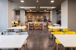 uma sala de jantar com mesas brancas e cadeiras amarelas em City Express Plus by Marriott Guadalajara Palomar em Guadalajara