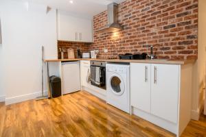 a kitchen with a brick wall and a washer and dryer at Cathedral View Rooms in Lincoln
