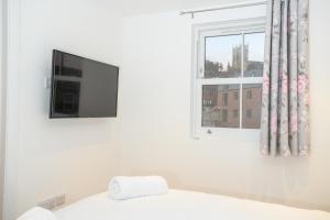 a white room with a tv and a window at Cathedral View apartments in Lincoln