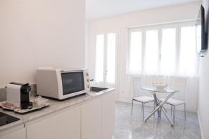 uma cozinha branca com uma televisão e uma mesa em Althea em Viareggio