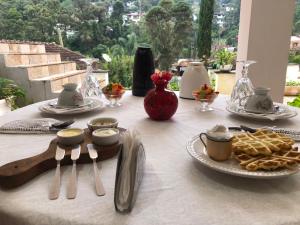 uma mesa com uma toalha de mesa branca com comida em Chalé Rosa do Vale em Petrópolis