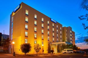 un edificio de hotel con una furgoneta estacionada frente a él en City Express by Marriott Zacatecas, en Zacatecas