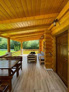 un gran porche de madera con bancos y una mesa en Casutele Din Moisei en Moisei