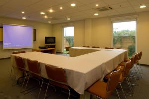 City Express by Marriott Mazatlan في مازاتلان: قاعة اجتماعات مع طاولة وكراسي وشاشة عرض