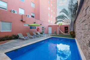 una piscina frente a un edificio rosa en City Express Junior by Marriott Merida Altabrisa, en Mérida