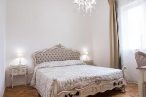 um quarto com uma cama com uma colcha branca e um lustre em Althea em Viareggio
