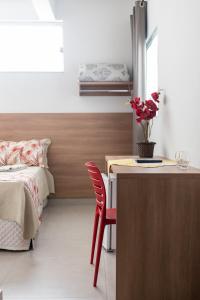 - une chambre avec un lit et un bureau orné d'un vase de fleurs dans l'établissement Hotel Central, à Boa Esperança