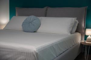 ein weißes Bett mit einem blauen Kissen darauf in der Unterkunft VELVET HOME PESCARA - Luxury Apartment in Pescara
