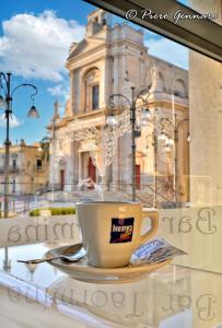 uma chávena de café sentada numa mesa em frente a um edifício em B&B del centro storico *** em Rosolini