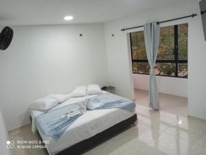 a white bedroom with a bed and a window at HOTEL SENDERO LAS GACHAS in Guadalupe