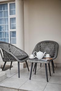 Duas cadeiras e uma mesa com um conjunto de chá em Mmaset Houses bed and breakfast em Gaborone