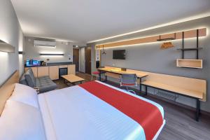ein Hotelzimmer mit einem großen Bett und einem Schreibtisch in der Unterkunft City Express by Marriott Tijuana Otay in Tijuana