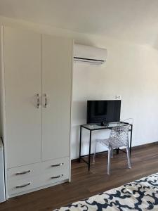 1 dormitorio con escritorio, TV y armario en Il Tramonto, en Giba