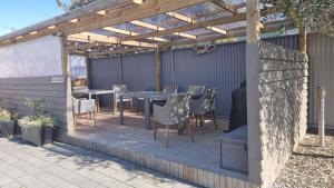 a patio with a table and chairs under a pergola at THE MEWS Oamaru in Oamaru