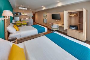 a hotel room with two beds and a desk at City Express Suites by Marriott Tijuana Rio in Tijuana