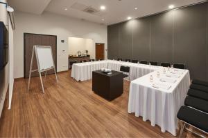 a conference room with white tables and chairs and a screen at City Express Suites by Marriott Tijuana Rio in Tijuana