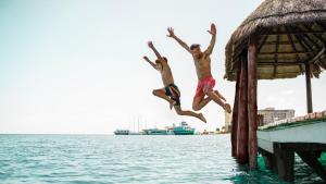 two boys jumping off a dock into the water at Holiday Inn Club Vacations The Royal Cancun All Inclusive in Cancún