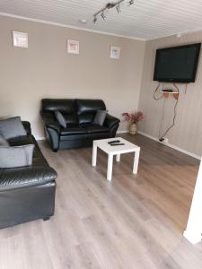 a living room with a black leather couch and a table at Herasbygda 