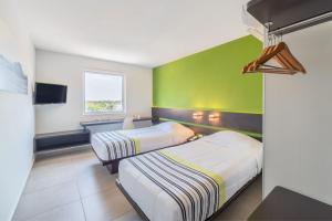 two beds in a room with a green wall at City Express Junior by Marriott Villahermosa in Villahermosa