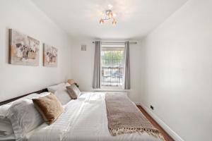 a white bedroom with a bed and a window at Cosy in Catford two bed near station in Beckenham