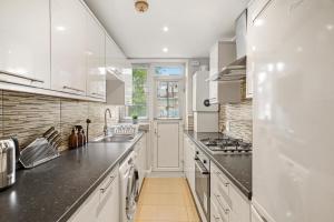 uma cozinha com armários brancos e um lavatório em Cosy in Catford two bed near station em Beckenham