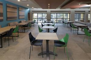 una cafetería con mesas, sillas y ventanas en City Express Plus by Marriott Monterrey Galerías, en Monterrey