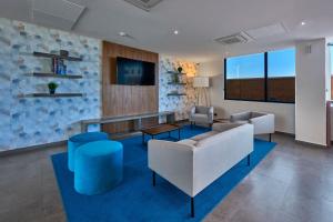 a living room with a couch and chairs and a tv at City Express by Marriott Hermosillo Expo in Hermosillo