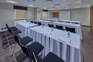 une salle de conférence avec des tables et des chaises blanches dans l'établissement City Express by Marriott Hermosillo Expo, à Hermosillo
