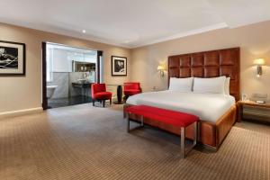 une chambre d'hôtel avec un lit et un banc rouge dans l'établissement The May Fair, A Radisson Collection Hotel, Mayfair London, à Londres