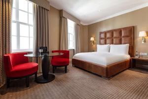 um quarto de hotel com uma cama, uma mesa e cadeiras em The May Fair, A Radisson Collection Hotel, Mayfair London em Londres