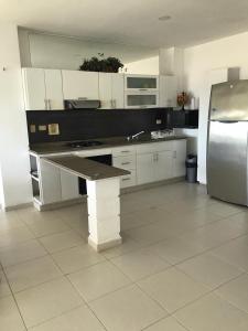 uma cozinha com armários brancos e um frigorífico em APARTAMENTO FRENTE A LA PLAYA EN COVEÑAS em Coveñas