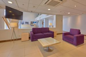 una sala de espera con 2 sillas de color púrpura y TV en City Express by Marriott Saltillo Sur en Saltillo