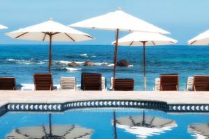 einen Pool mit Sonnenschirmen und Stühlen sowie das Meer in der Unterkunft Luxury Modern Punta Mita Condo 3 bdrm, sleeps 8 with Golf access in Punta Mita